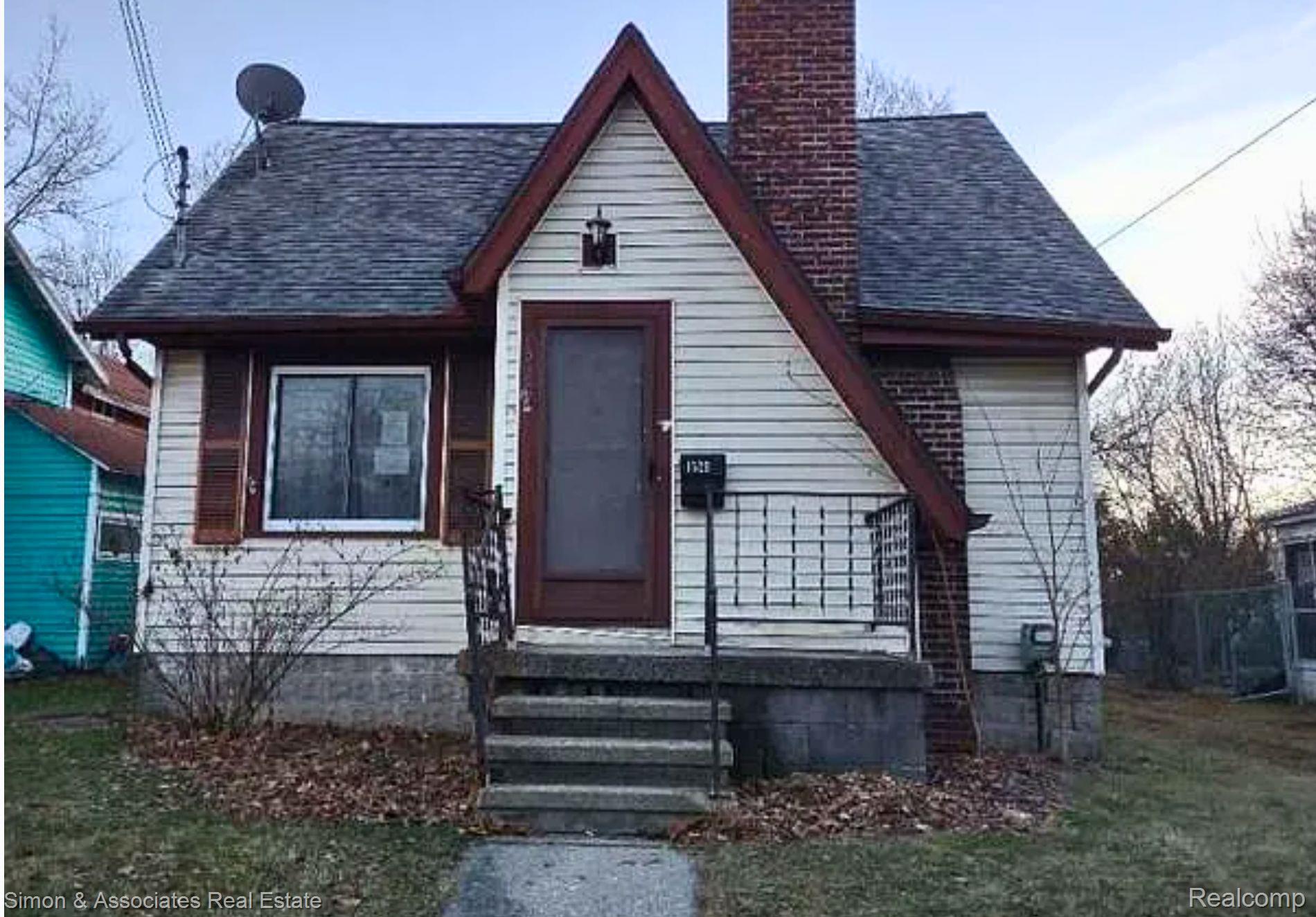 Gable-front home featuring white siding and a prominent brick chimney
