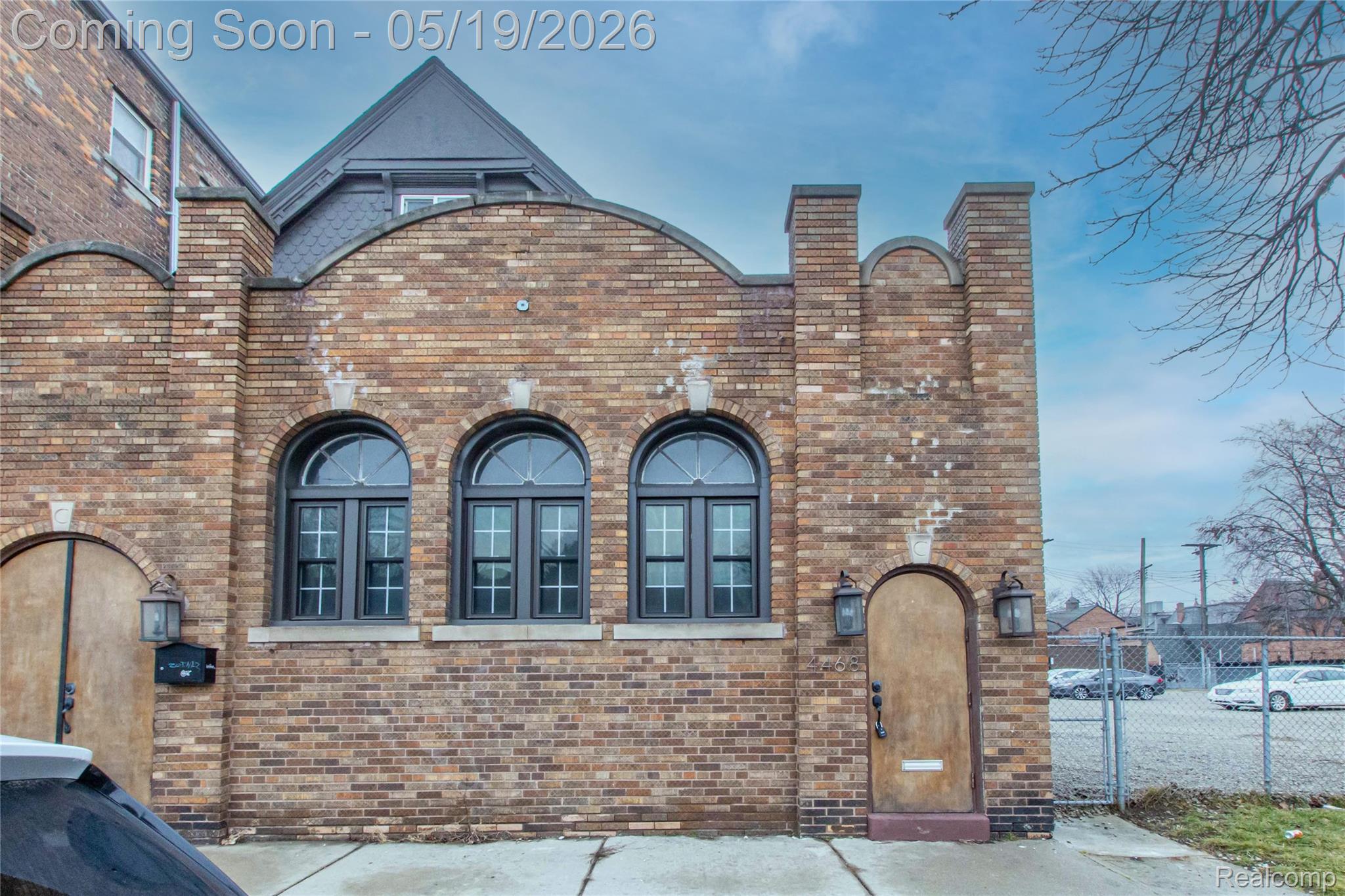 View of side of home with brick siding and a gate