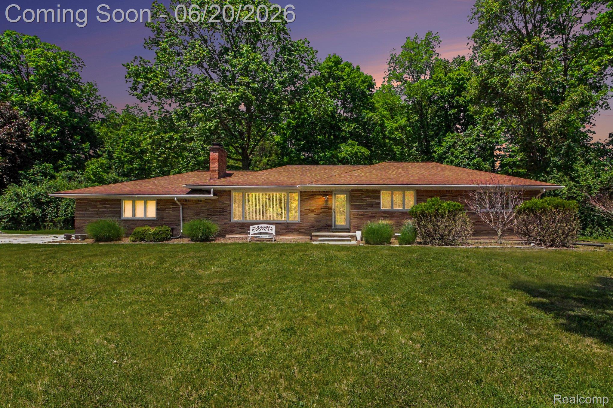 Brick exterior ranch home featuring a prominent chimney, a large picture window, and a front entry with a sidelight
