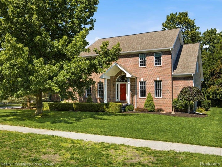Brick exterior, covered entry, gabled roofline, front yard, mature trees