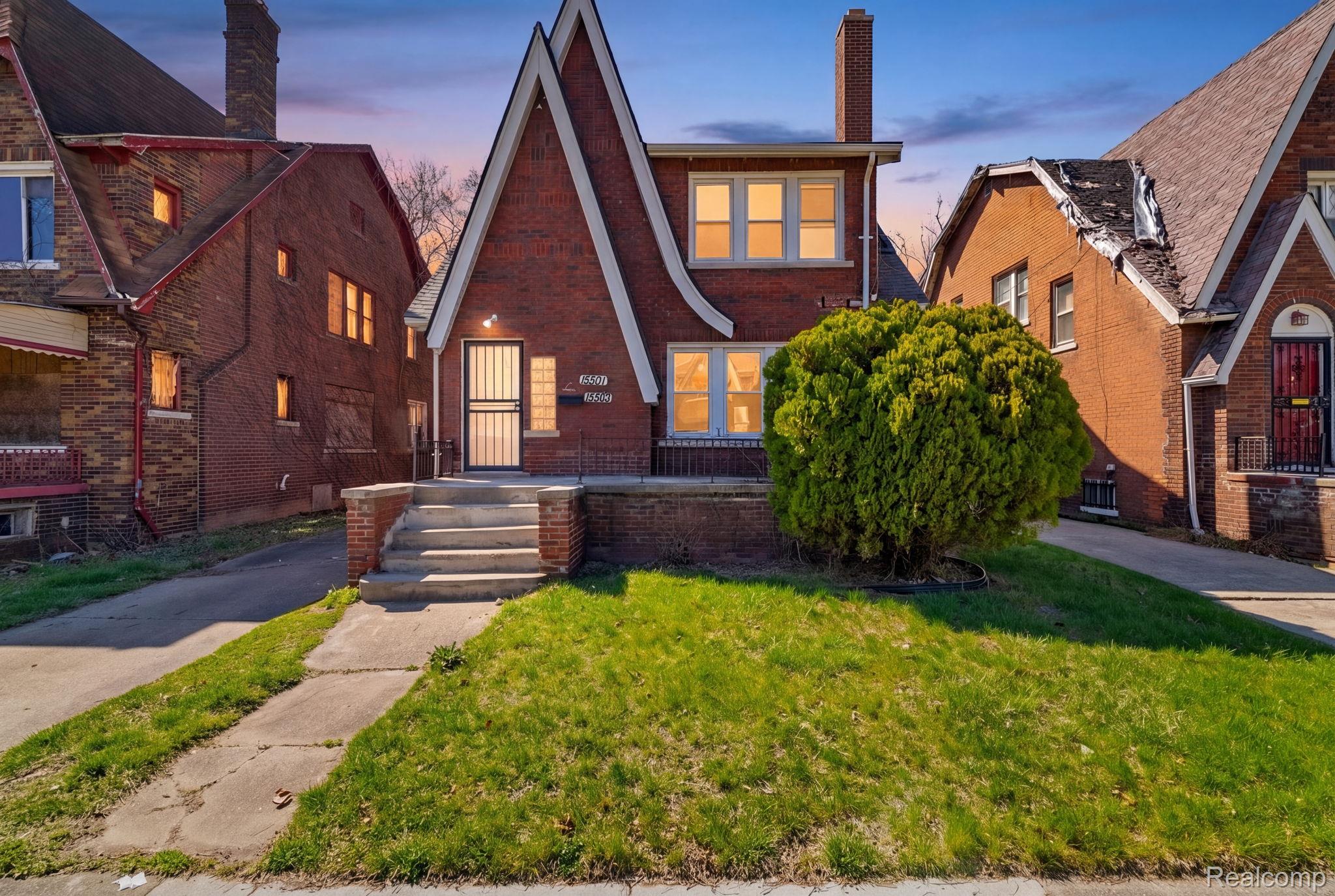 Tudor-style house with brick siding, a yard, and a chimney