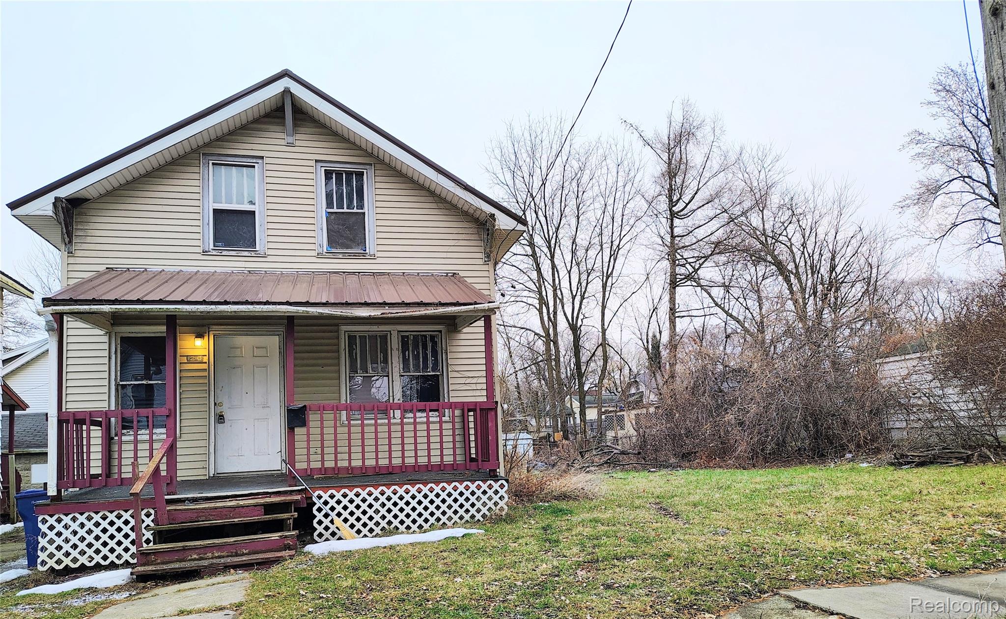 View of front of property with a porch, a front yard, and a metal roof