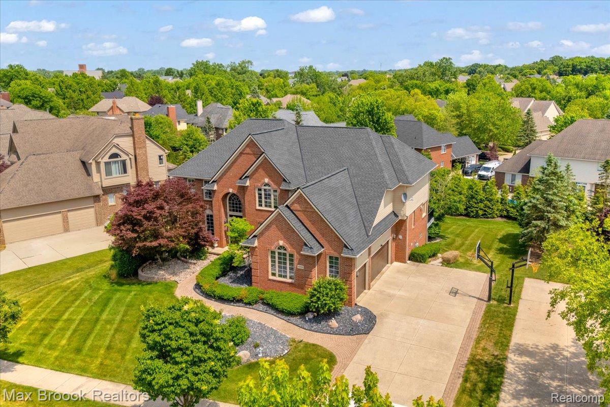 Aerial view of home. Brick exterior featuring an arched entryway, multiple gabled rooflines, and a paved walkway