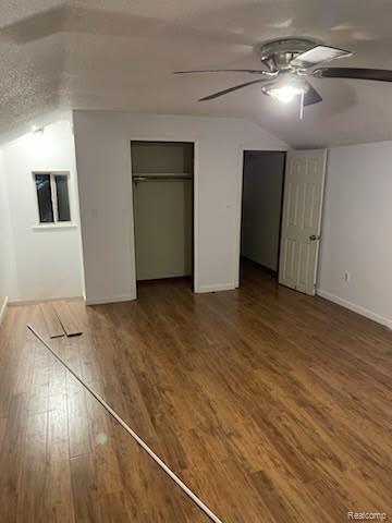 Bright room featuring wood-finish flooring, a ceiling fan with integrated lighting, a built-in closet with a hanging rod, and a white interior door