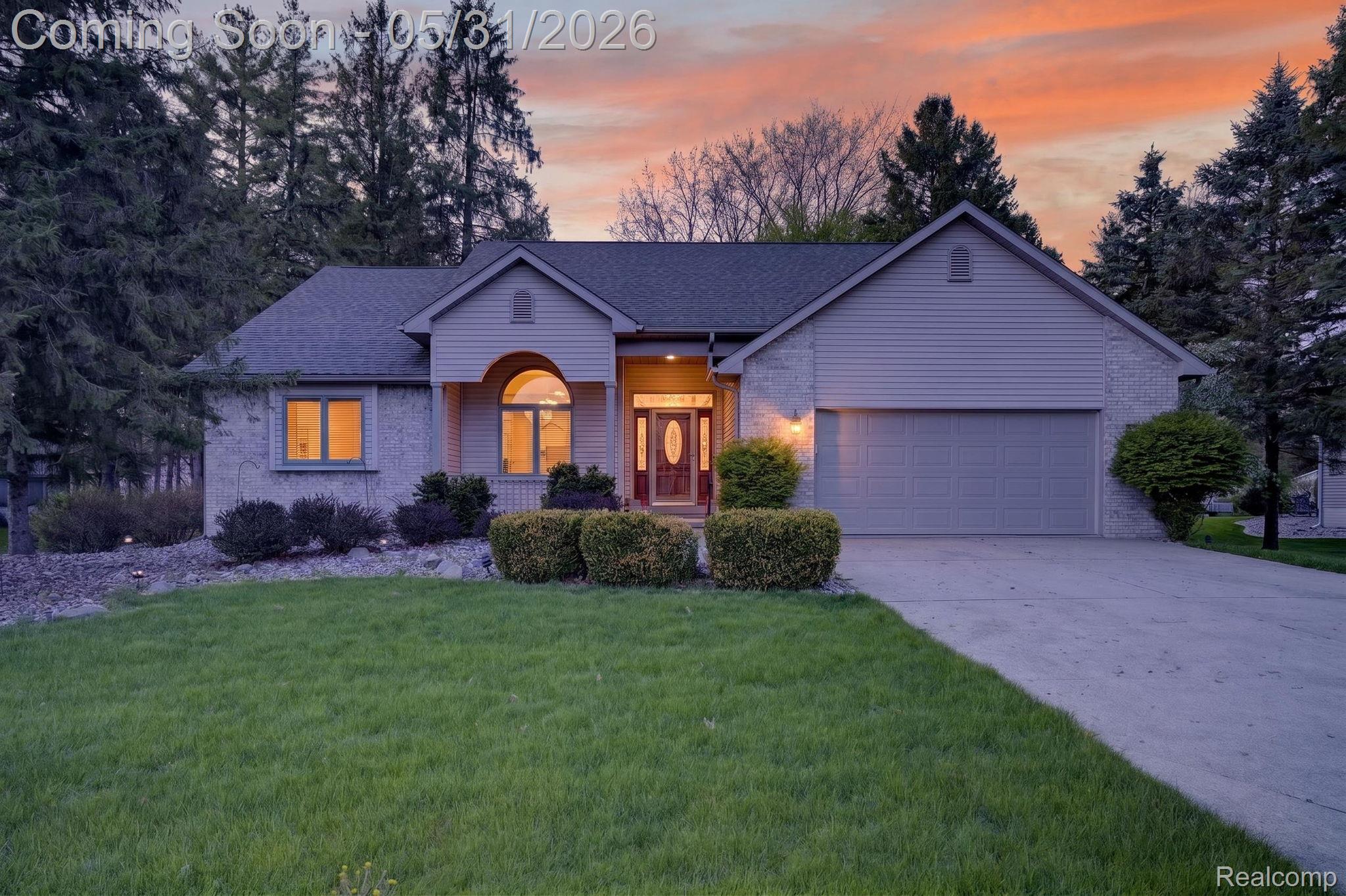 View of front of home with a front lawn, an attached garage, brick siding, concrete driveway, and a shingled roof