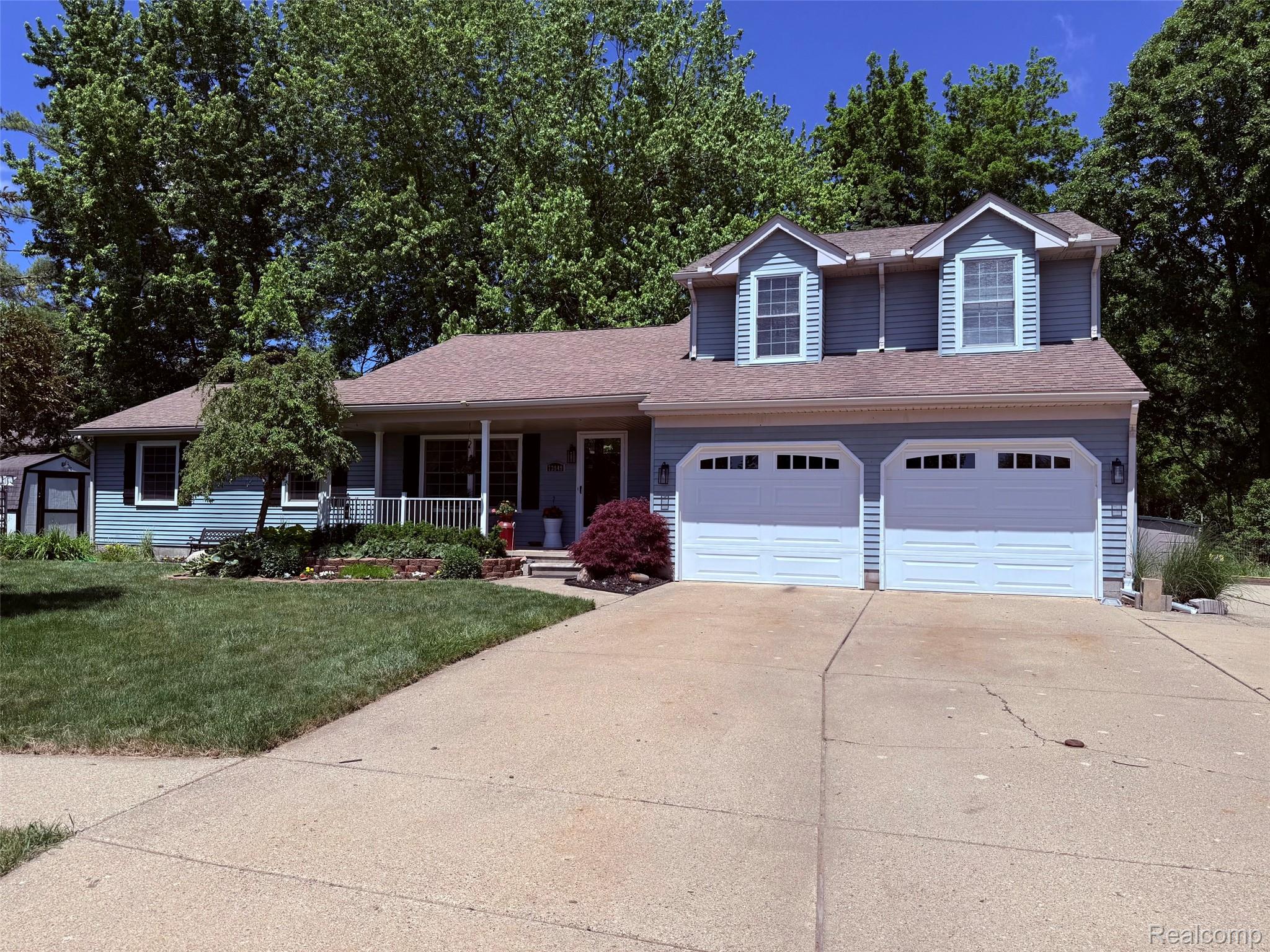 Two-story residential exterior with light blue horizontal siding and a brown shingle roof