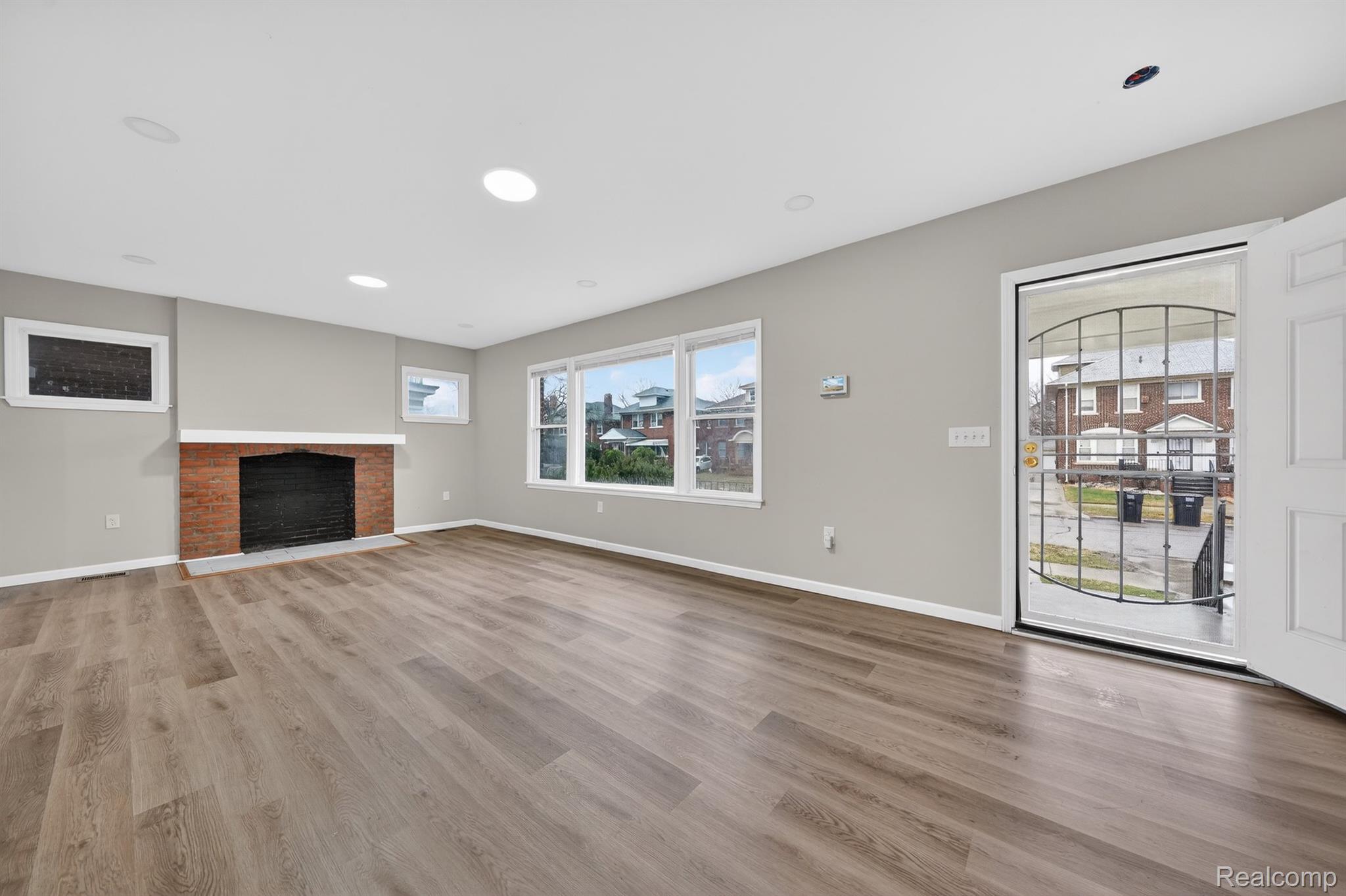 Unfurnished living room featuring a brick fireplace, light wood-type flooring, and recessed lighting
