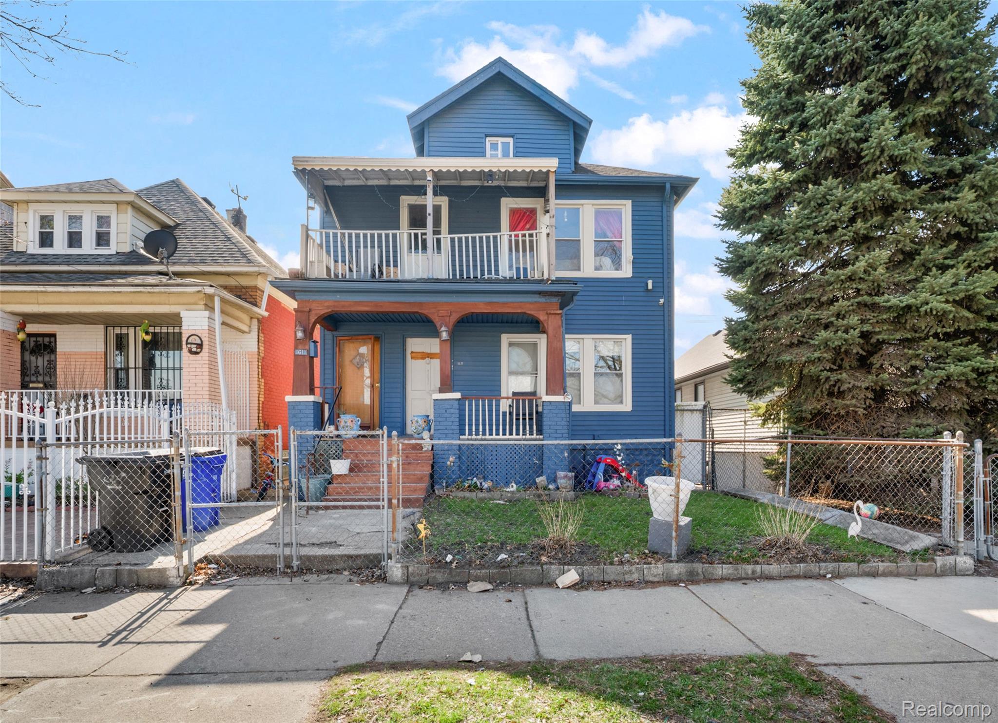 View of front of property with a porch, a gate, a fenced front yard, and a balcony