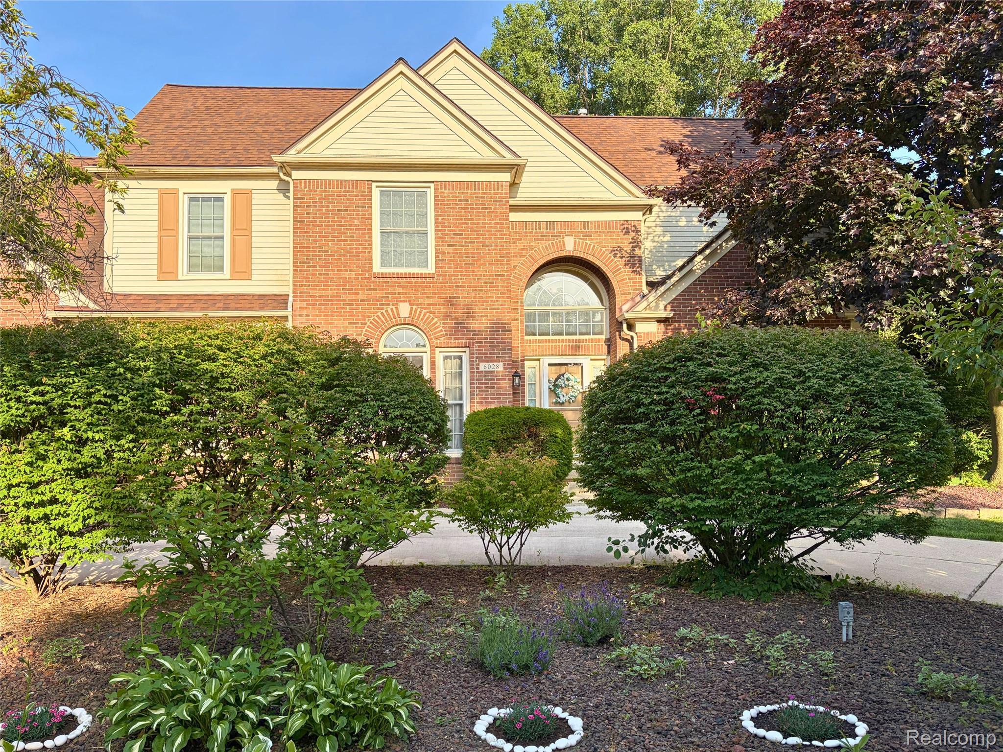 Brick and siding facade featuring a prominent arched window above the entry