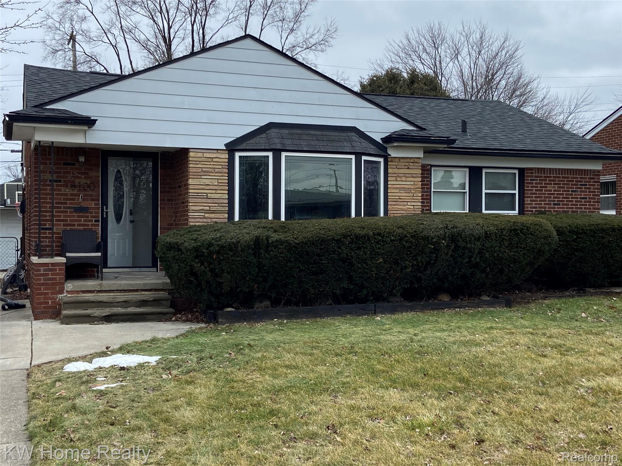 View of front of property featuring brick siding, a front yard, and a shingled roof