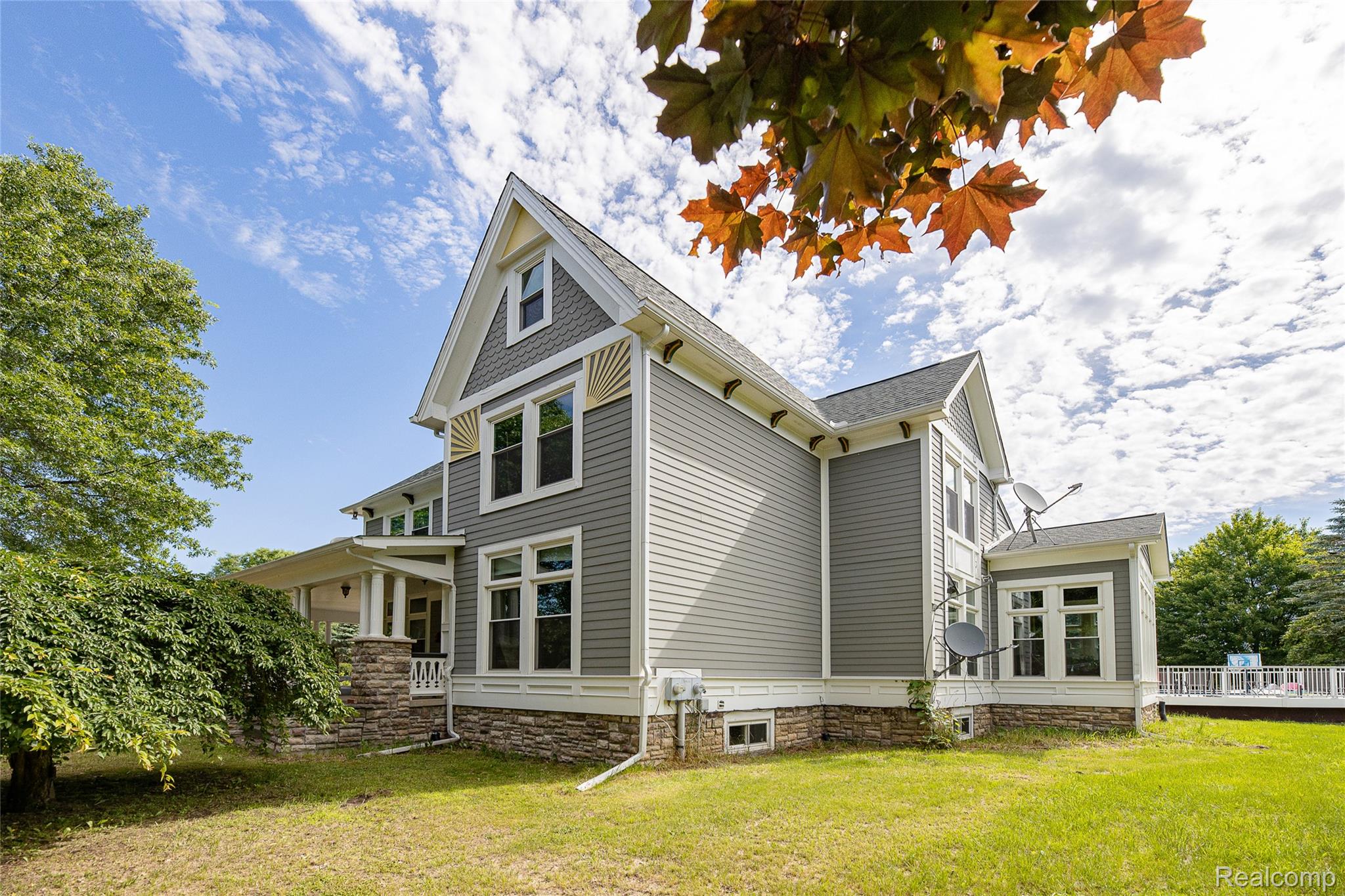 Multi-level residence featuring gray siding with white trim accents and a stone foundation