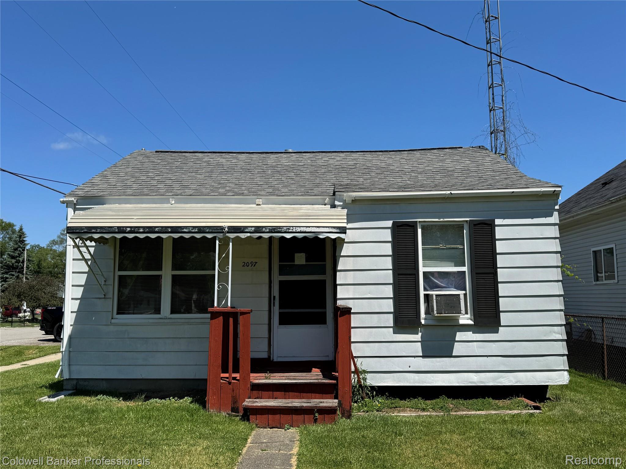Single-story home featuring light-colored siding and a dark shingle roof