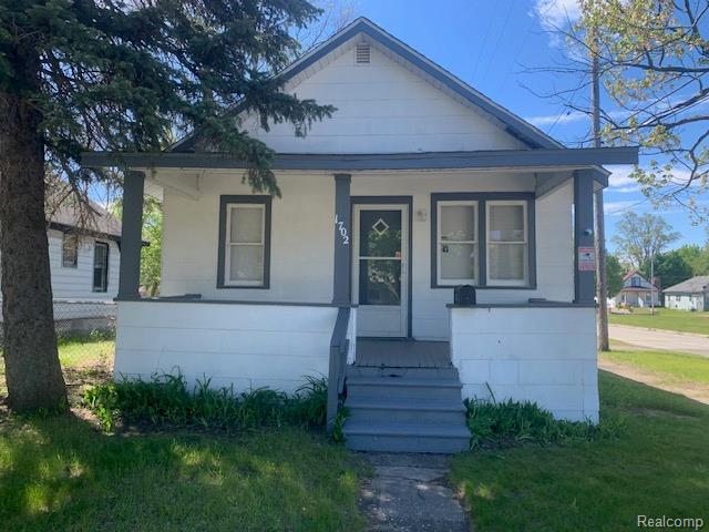 Bungalow featuring a porch and a front lawn