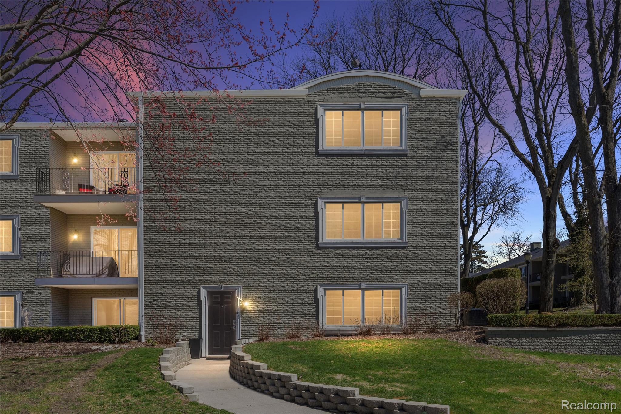 Traditional-style home with a front yard, a balcony, and brick siding