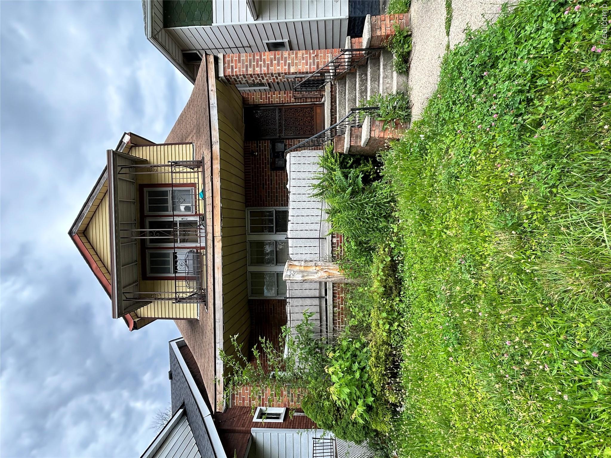 Two-story residence featuring a brick first level and yellow siding on the second level, complemented by a gabled roof