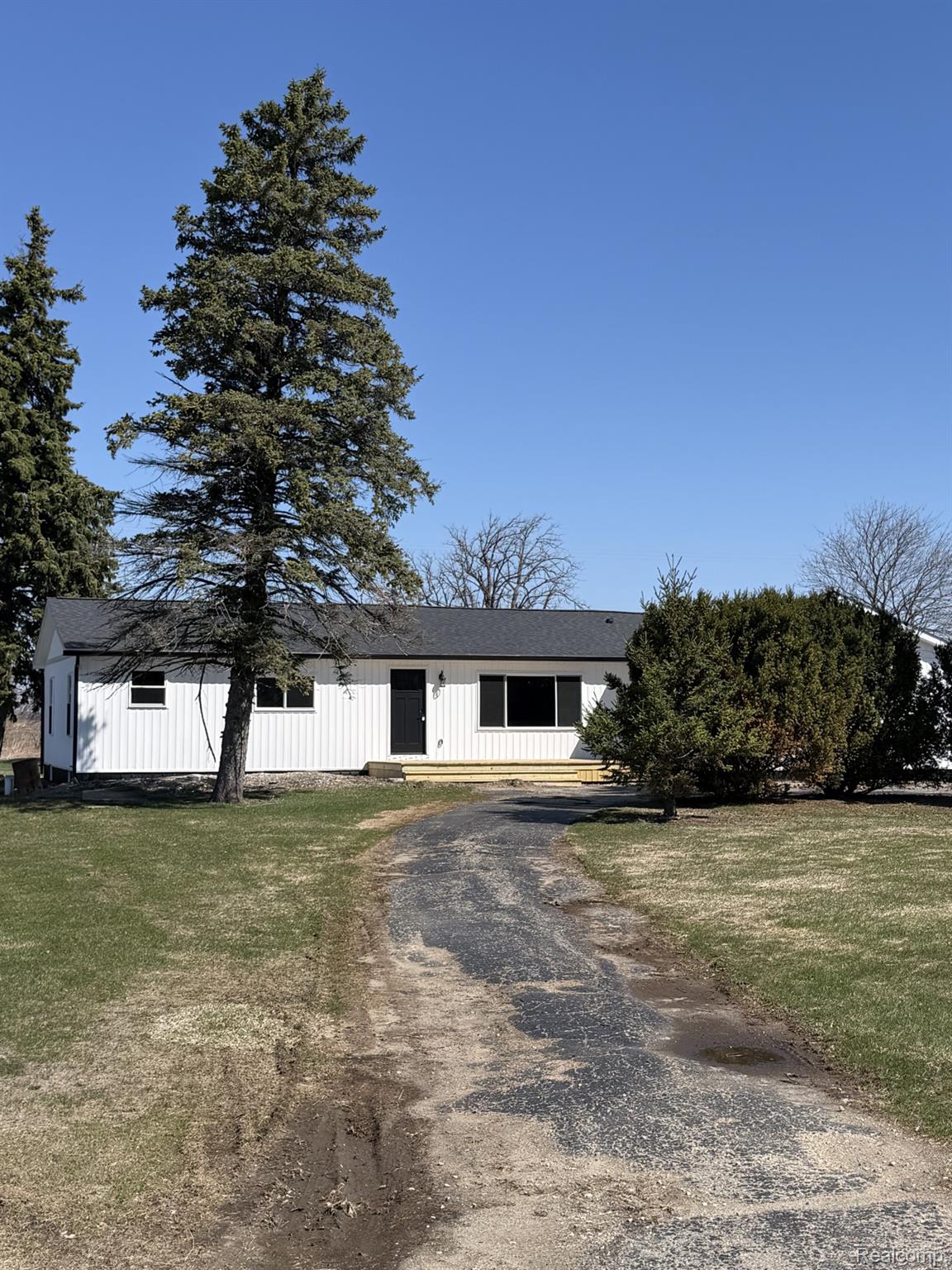 View of front of house with driveway, board and batten siding, and a front lawn