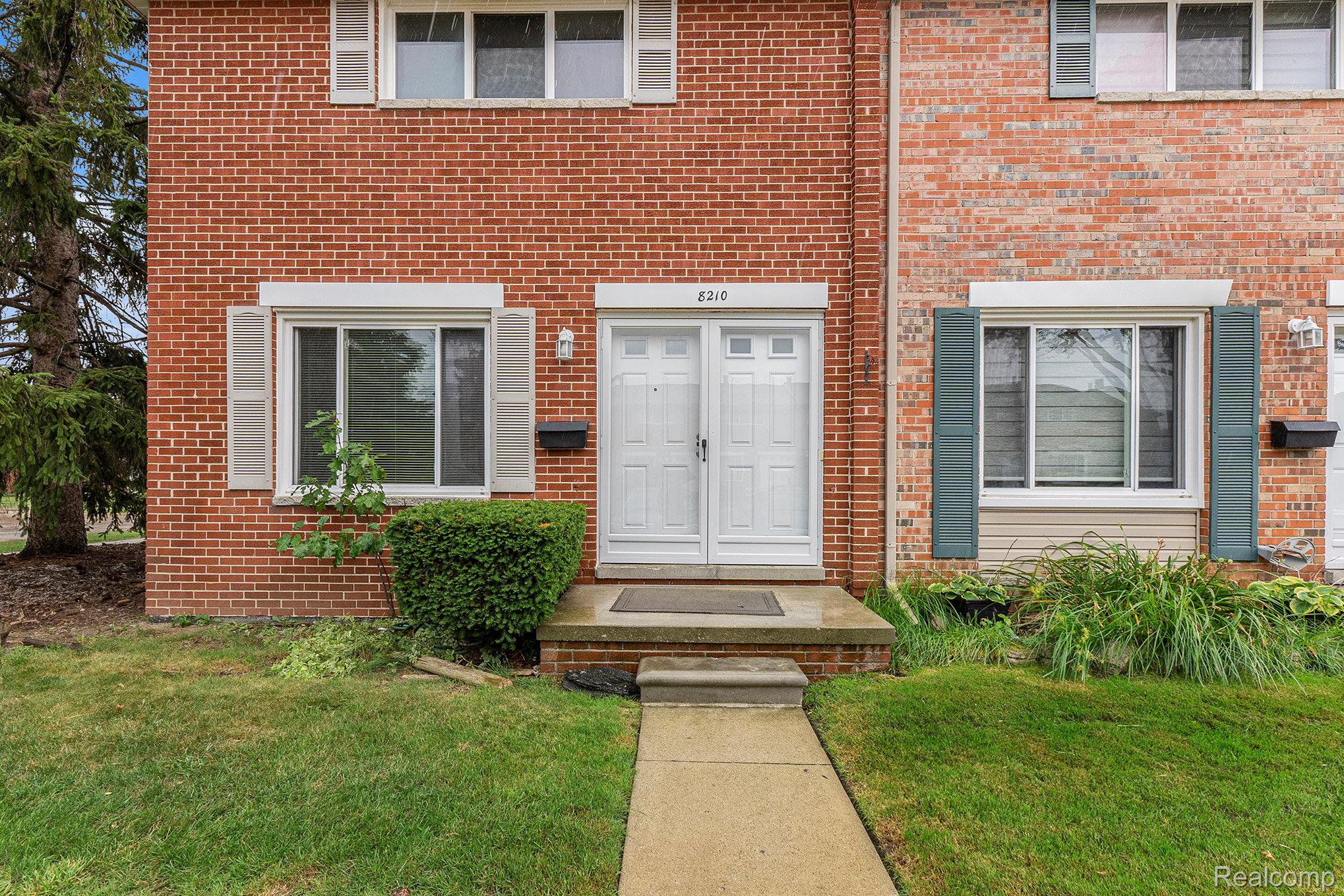 View of exterior entry with brick siding and a lawn