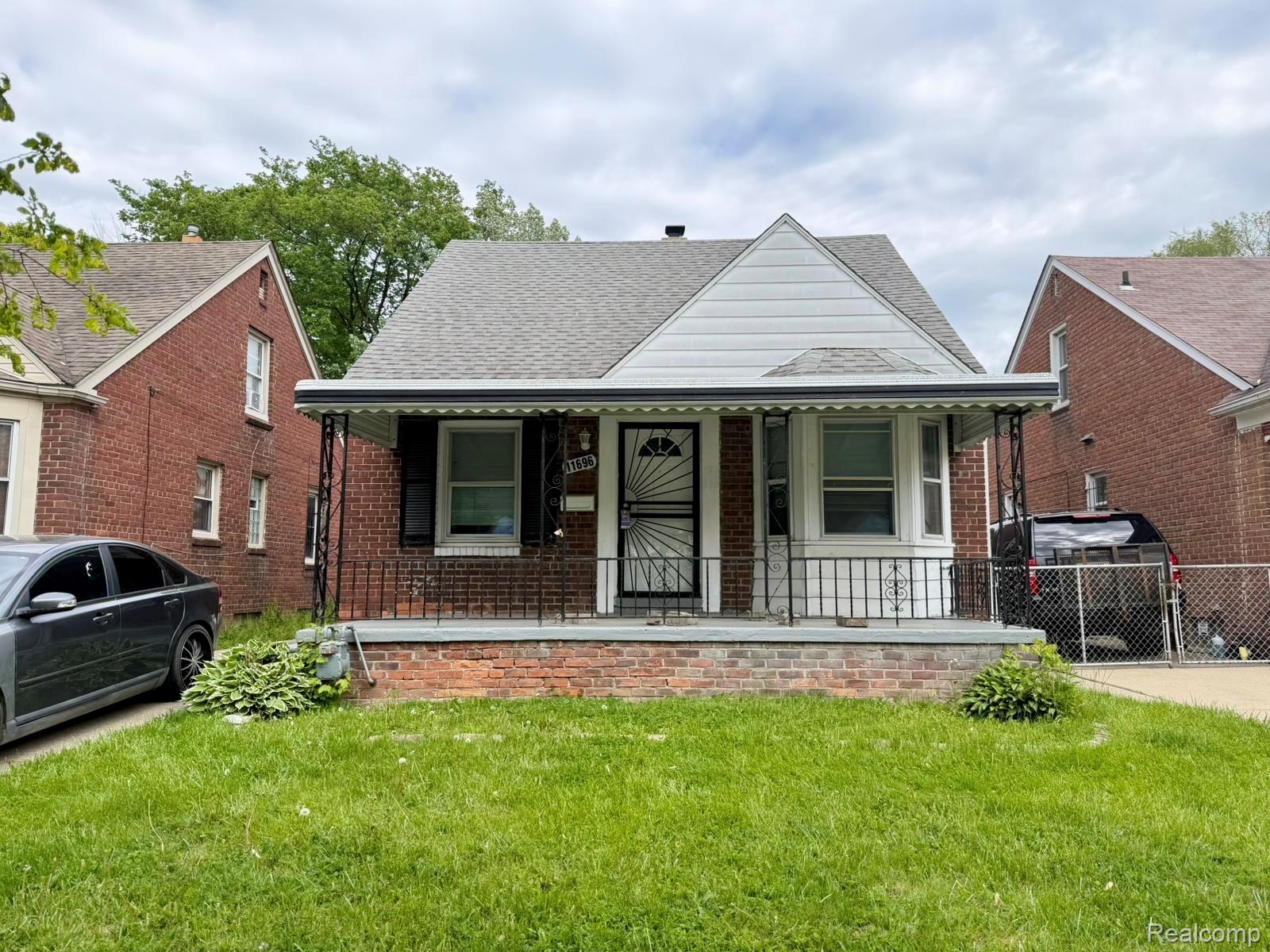 Brick home with a covered front porch featuring wrought iron railing