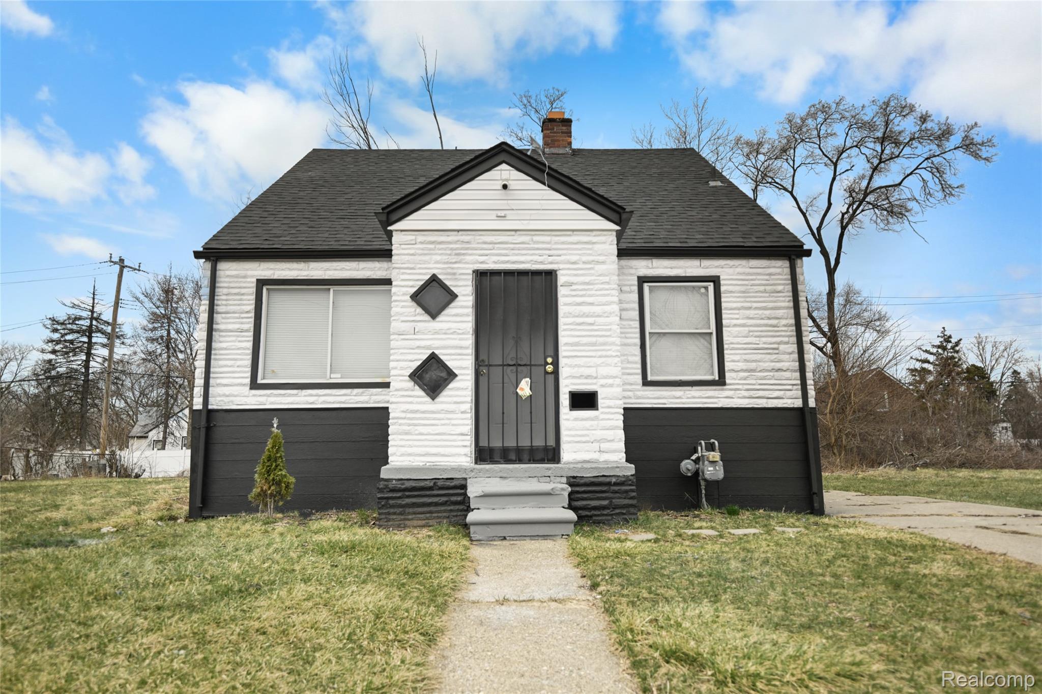 Bungalow with a front lawn, a chimney, roof with shingles, and entry steps