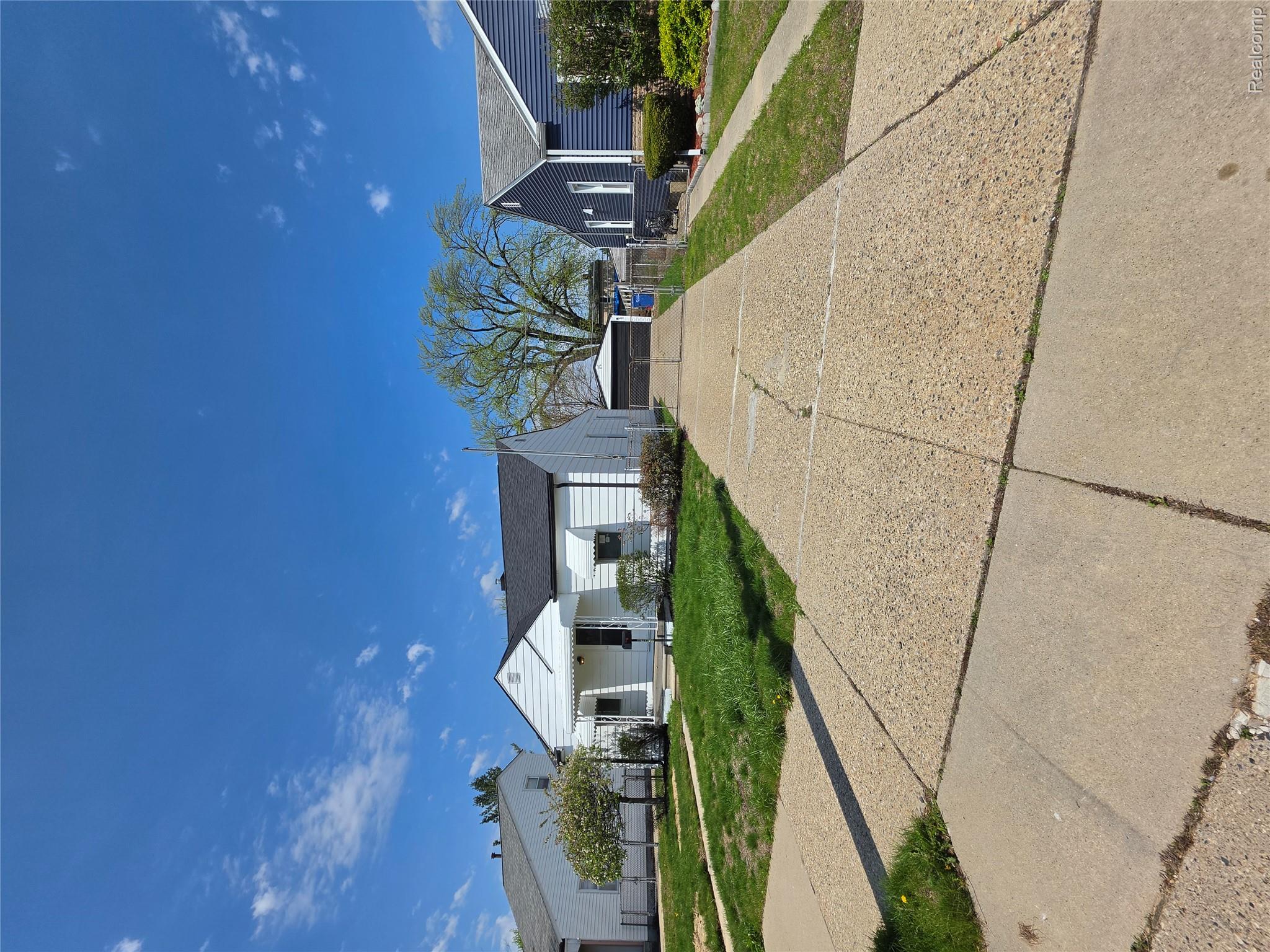 Bungalow with covered porch, a front lawn, a residential view, and a detached garage