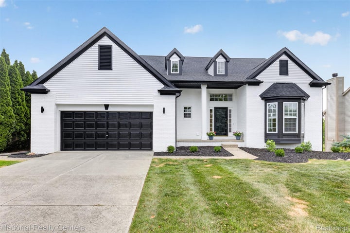 Contemporary facade featuring white brick and siding, a black shingled roof, and dark trim accents