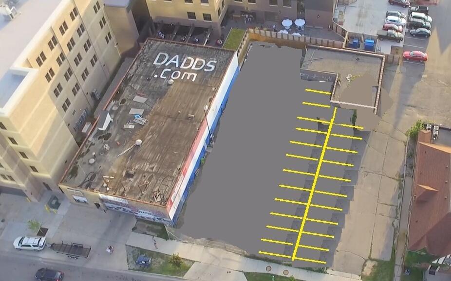 Aerial view of commercial buildings beside a large parking area marked with yellow spaces.