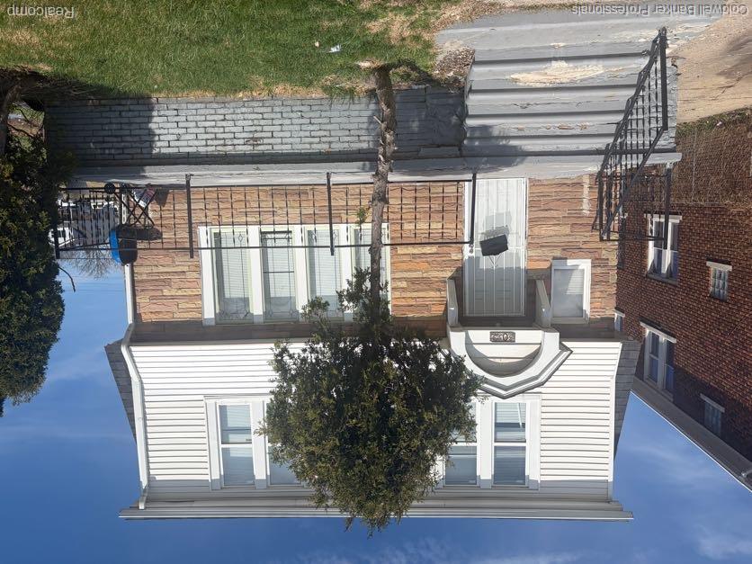 Two-story residence featuring a combination stone and siding facade, a covered front entry, and a front porch with wrought iron railings