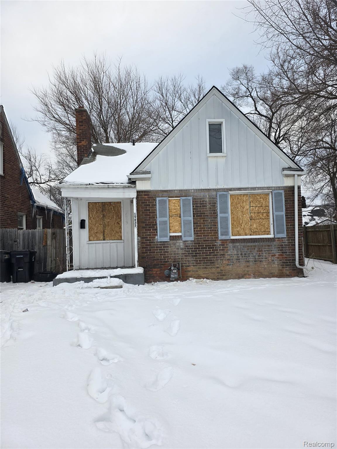 View of front facade featuring brick siding, a chimney, and board and batten siding