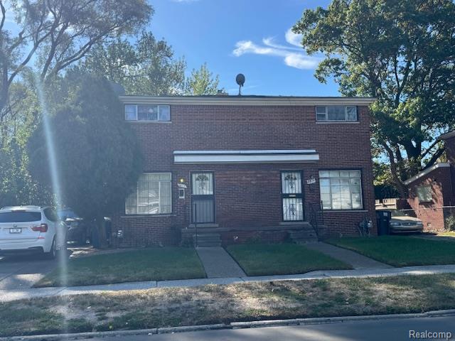 Traditional-style house featuring brick siding and a front lawn