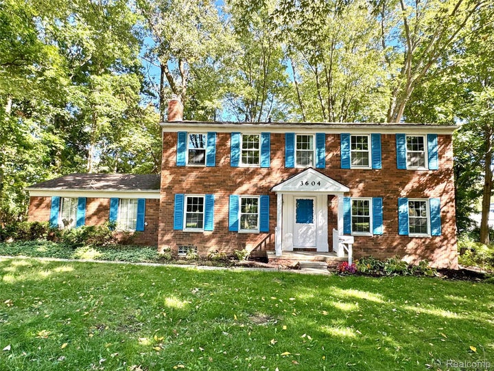 Brick facade exterior with contrasting blue shutters, white trim, and a covered entry