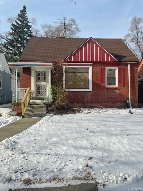 Bungalow-style home with a shingled roof, brick siding, and a porch
