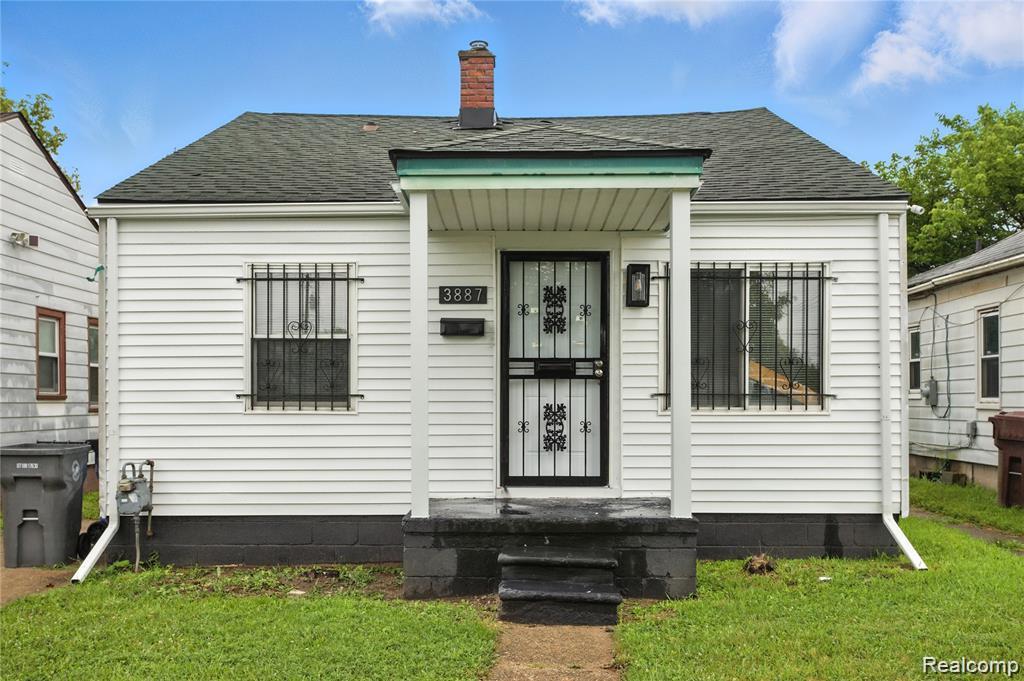 White siding exterior with a dark shingle roof, covered entry porch, dark security screen door, and exterior chimney
