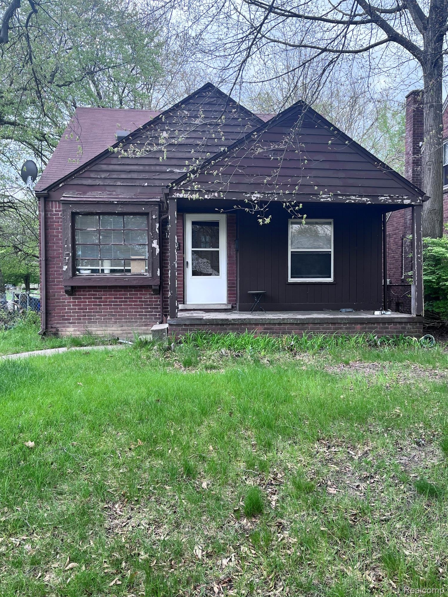 Bungalow-style house featuring a porch, a front lawn, and brick siding
