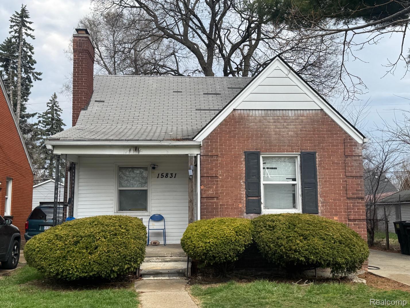 Bungalow featuring brick siding, a chimney, and roof with shingles
