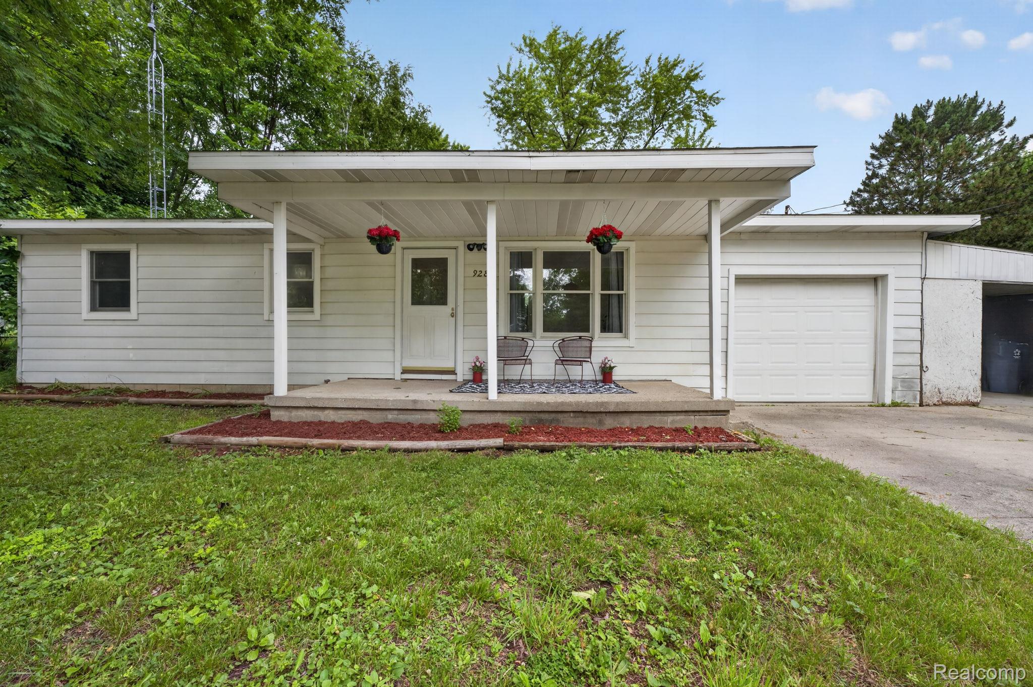 White siding exterior with an attached garage, covered front porch, and a concrete driveway