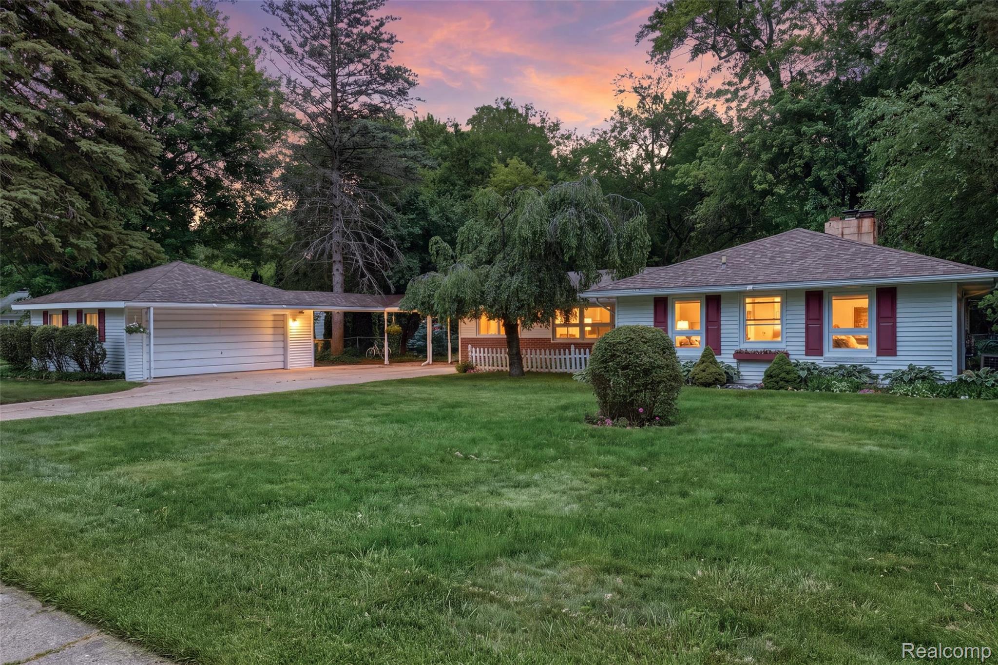 Ranch-style residence featuring white siding, red window shutters, and a covered carport connecting to an attached garage