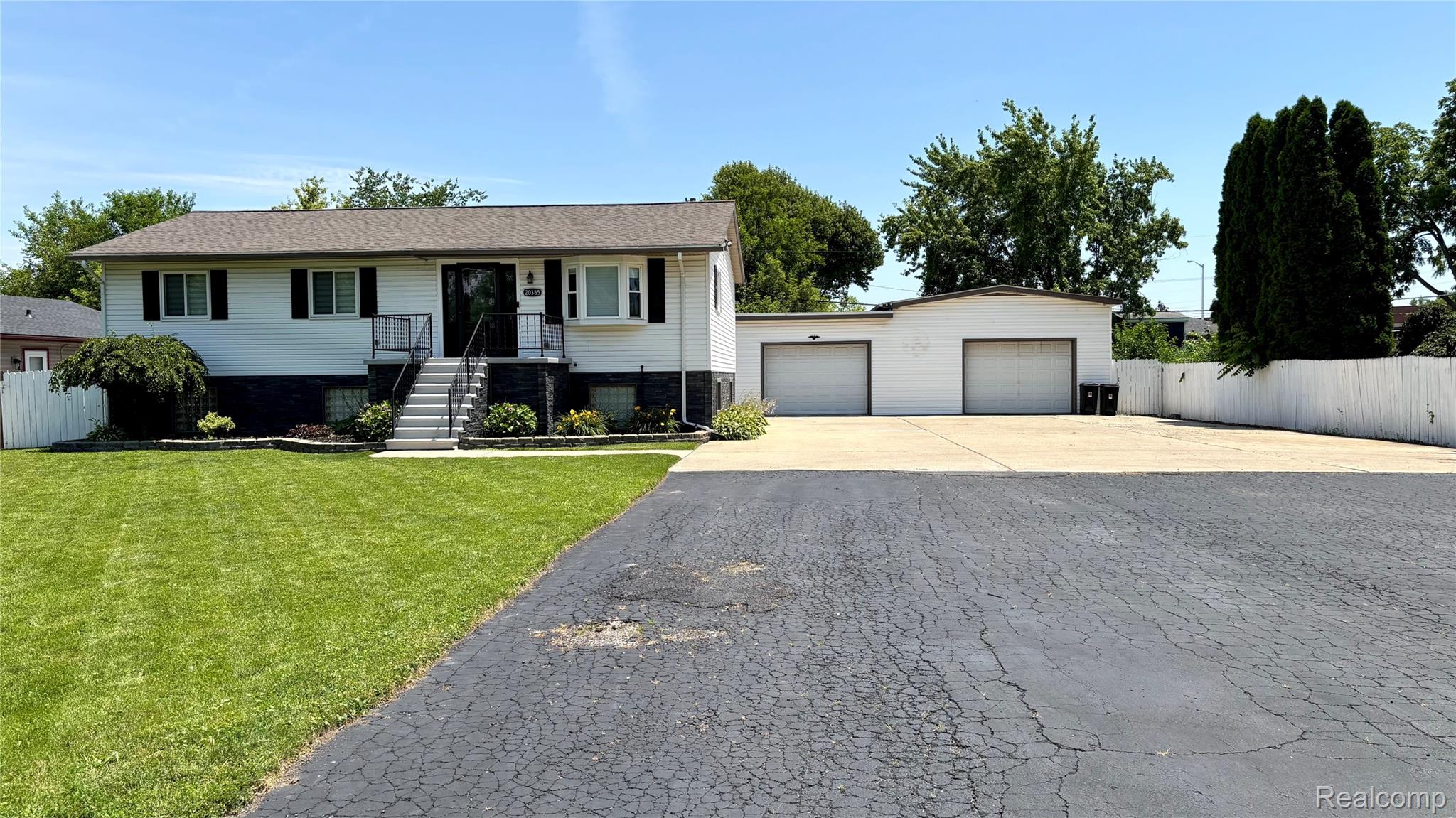 Split-level residence featuring white siding and black foundational accents