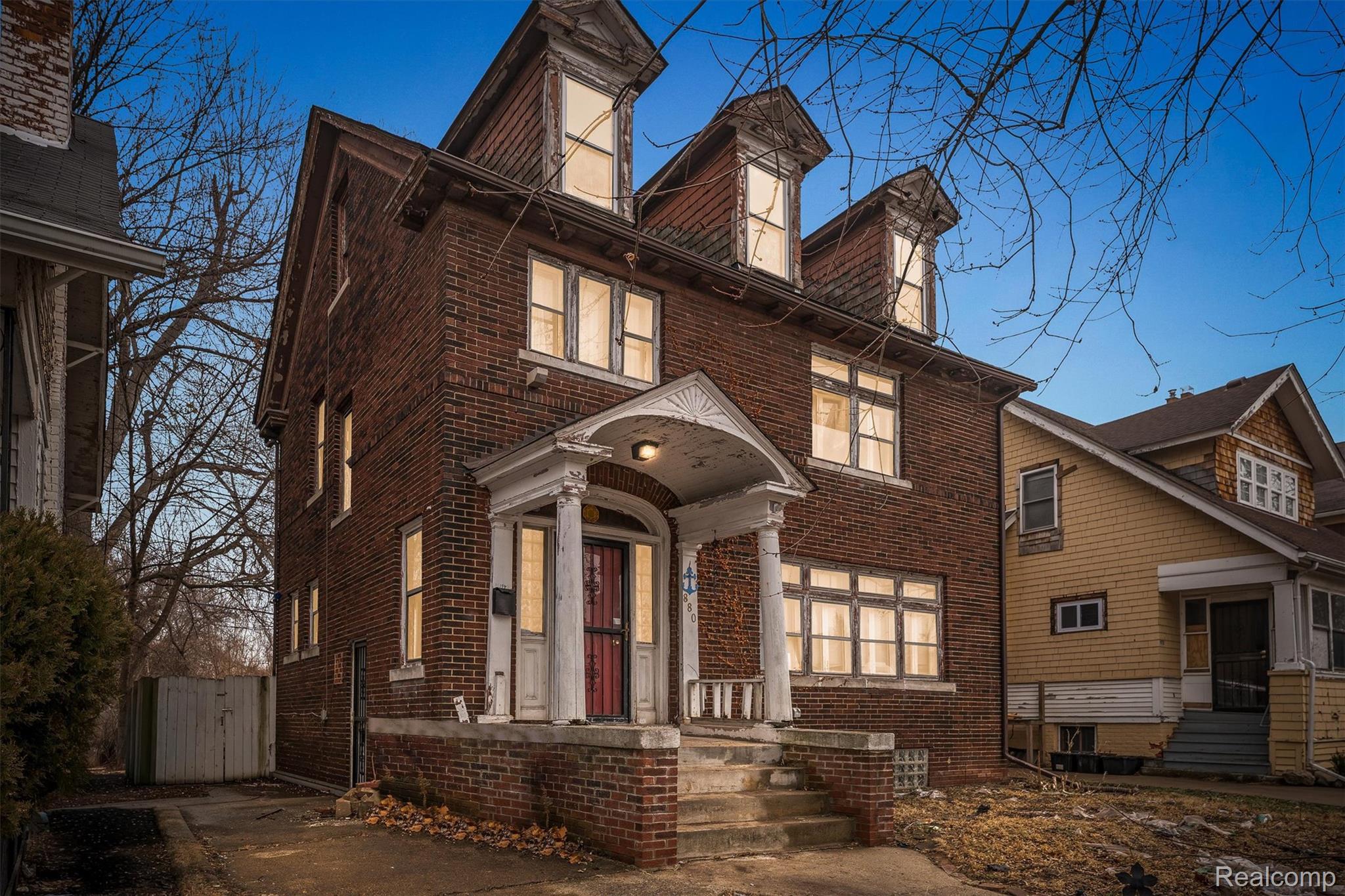 View of front of house with a gate and brick siding