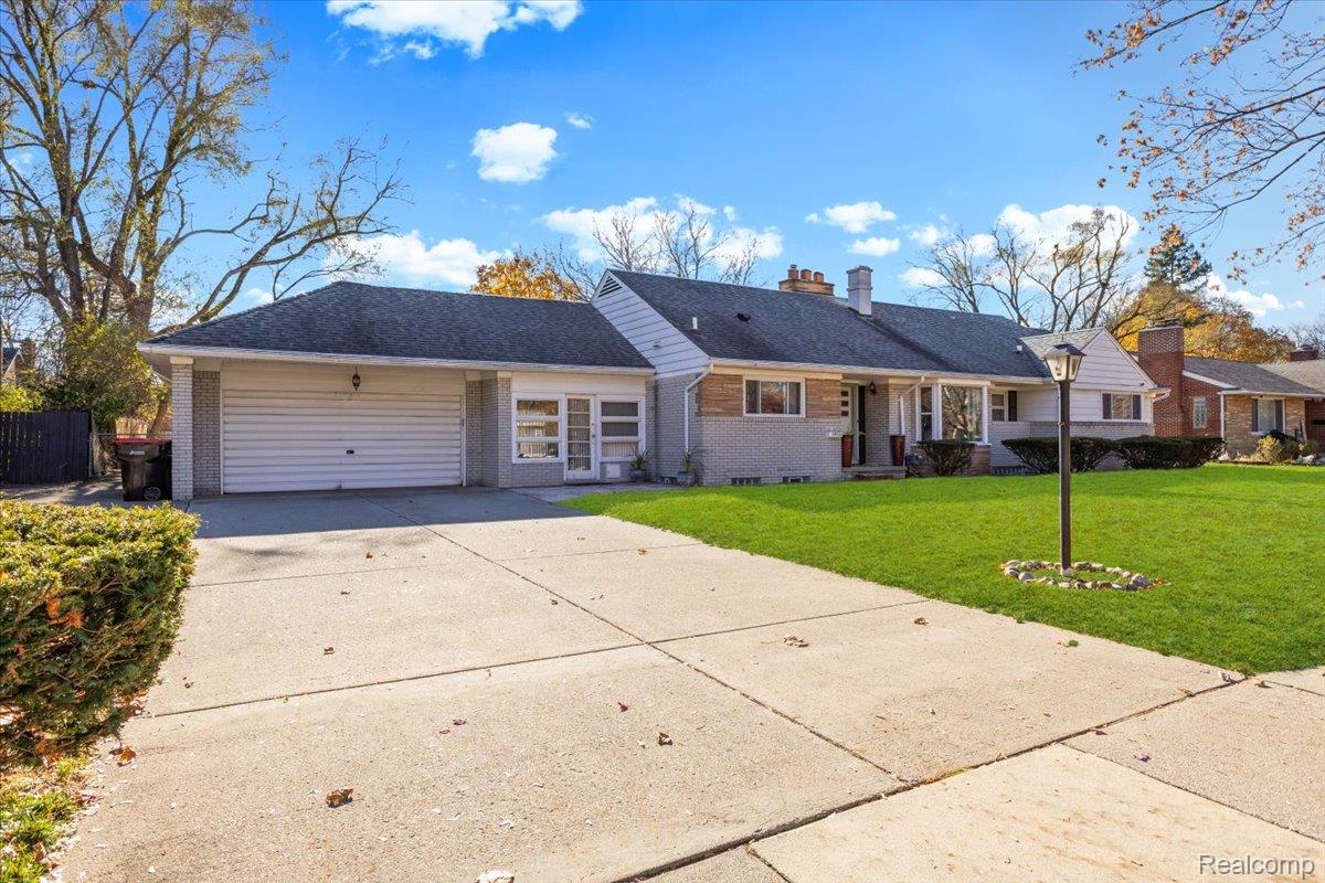 View of front facade with brick siding, a front lawn, concrete driveway, and an attached garage
