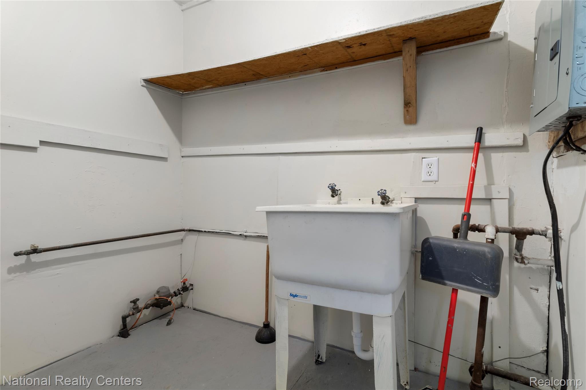 Laundry area with unfinished concrete floors and electric panel