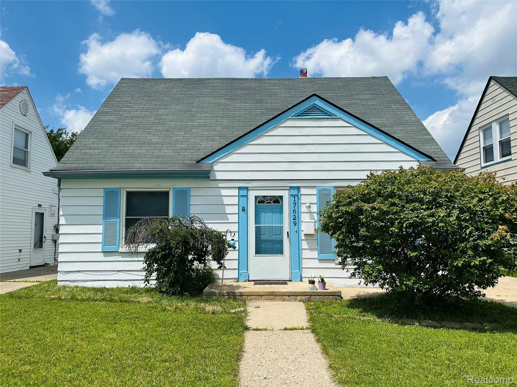 White siding bungalow with blue accented gable, shutters, and front door