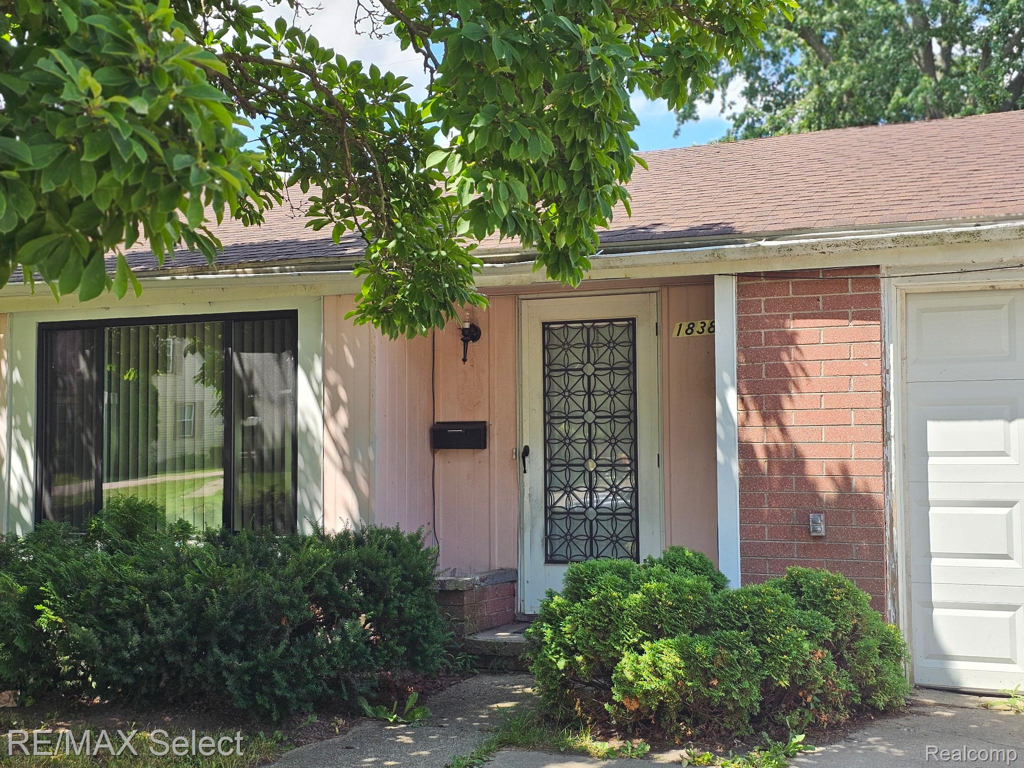Siding and brick exterior featuring a white paneled garage door and a front door with decorative security grate