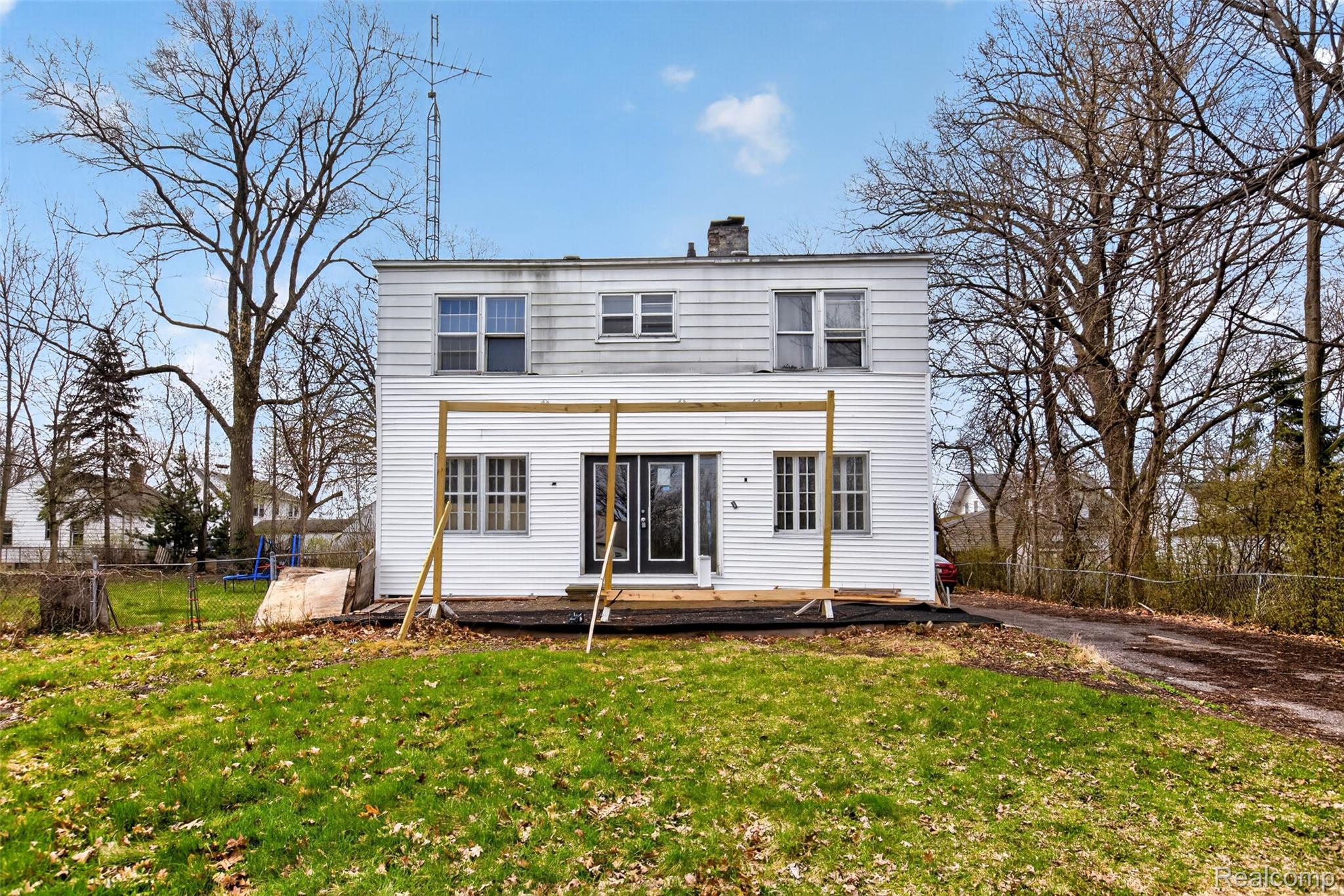 View of front of home with a fenced backyard, a chimney, a deck, and french doors