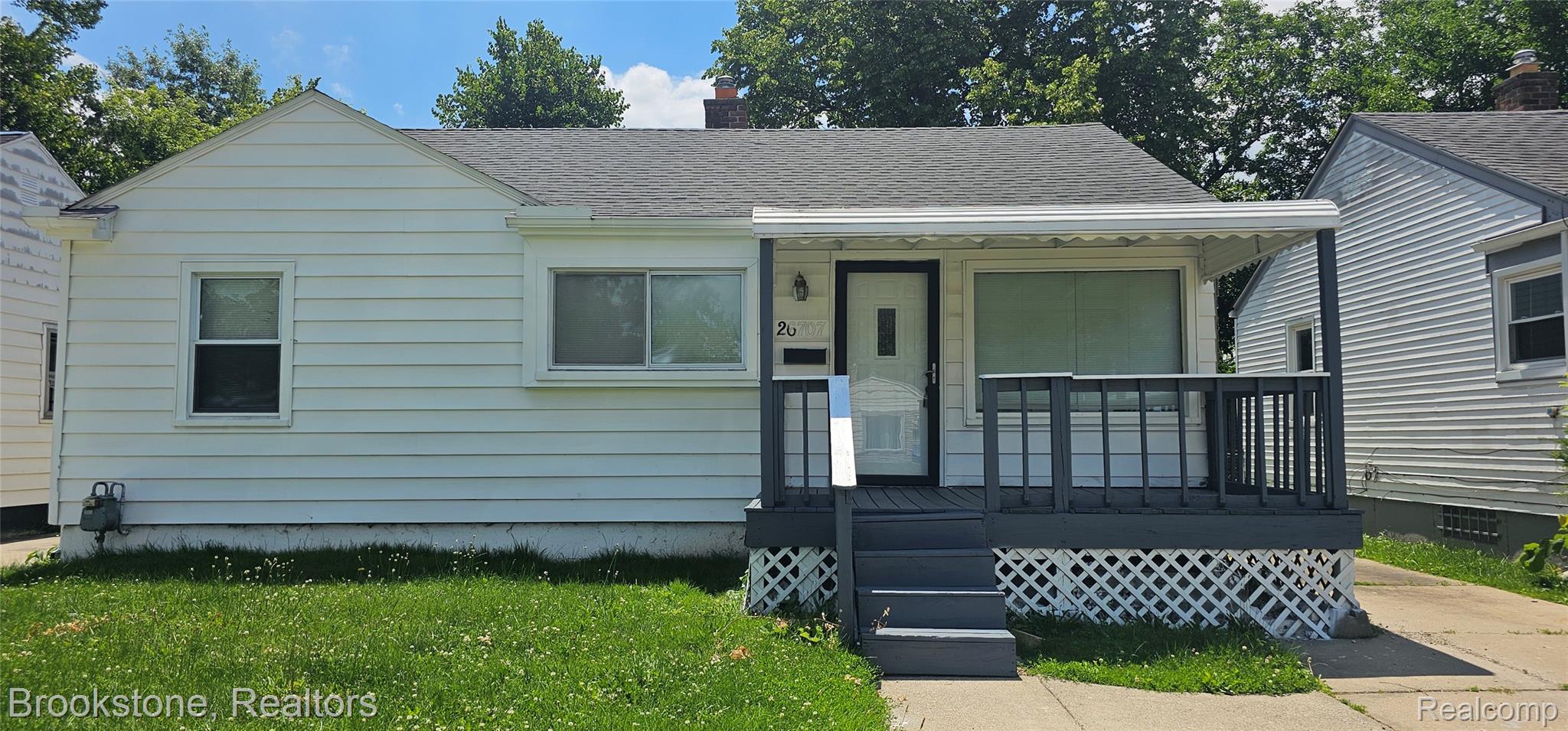 White siding exterior featuring a covered front porch with dark grey railings and steps
