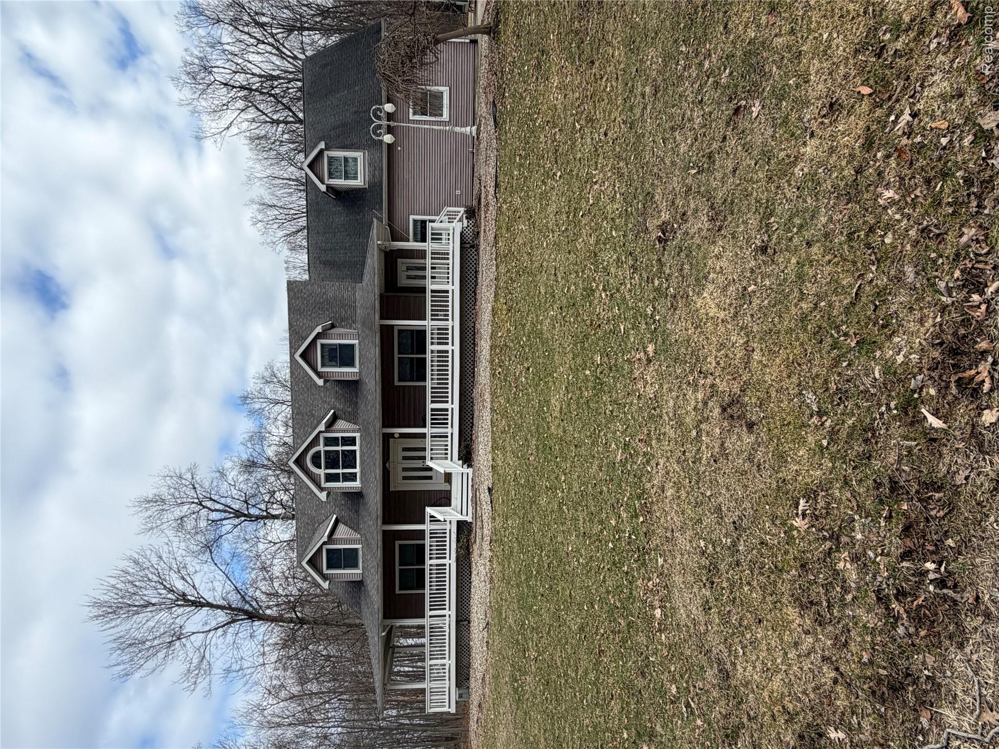 View of front of property with covered porch, a front yard, and a shingled roof