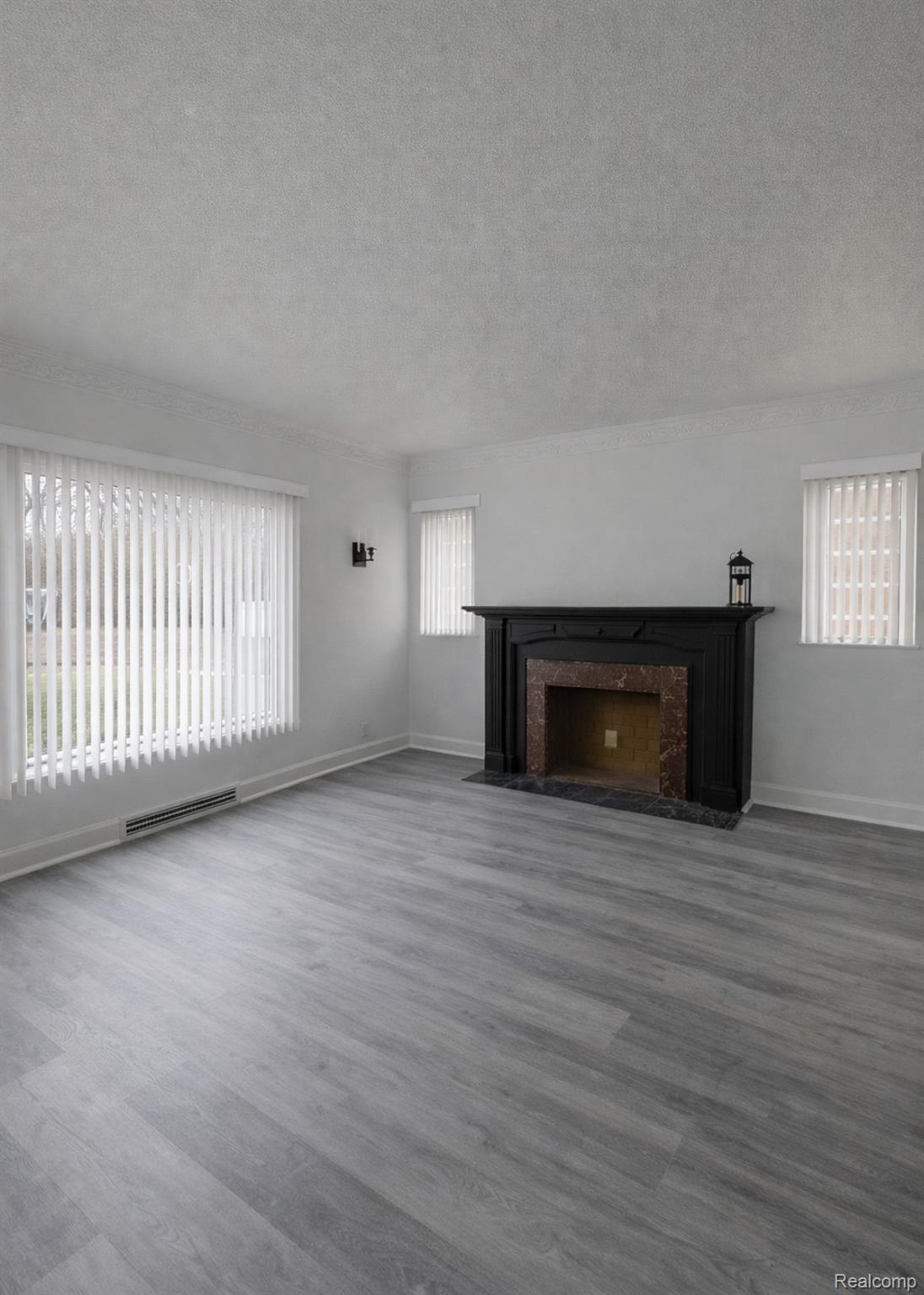 Unfurnished living room featuring a high end fireplace, wood finished floors, and a textured ceiling