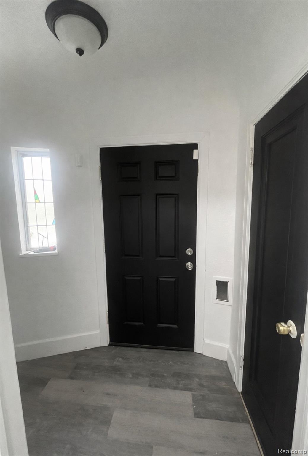 Foyer with dark wood-style floors and baseboards
