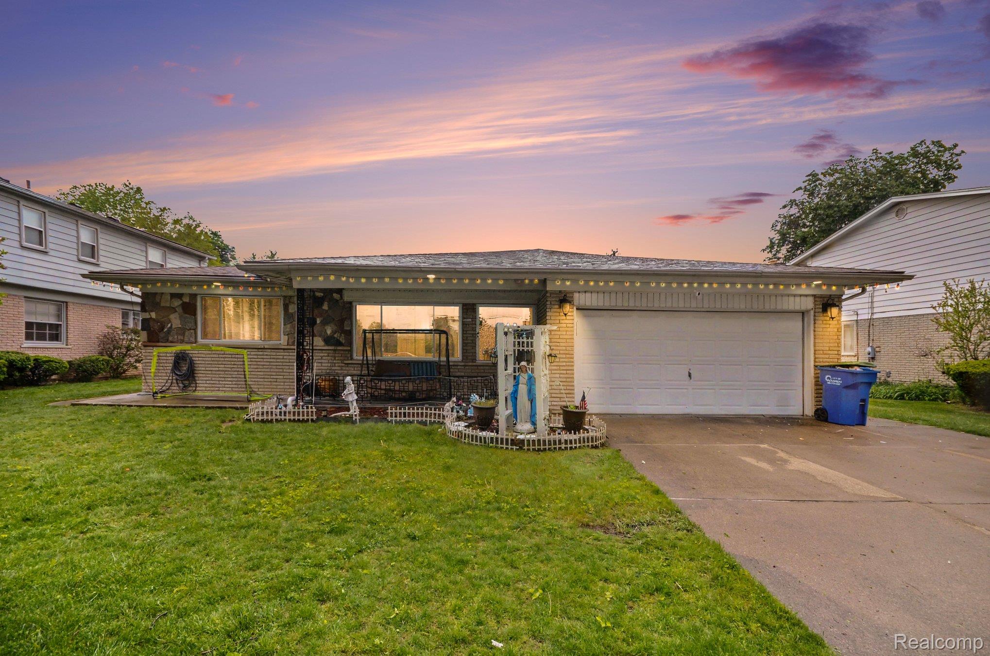 View of front of property featuring brick siding, concrete driveway, an attached garage, and a front yard