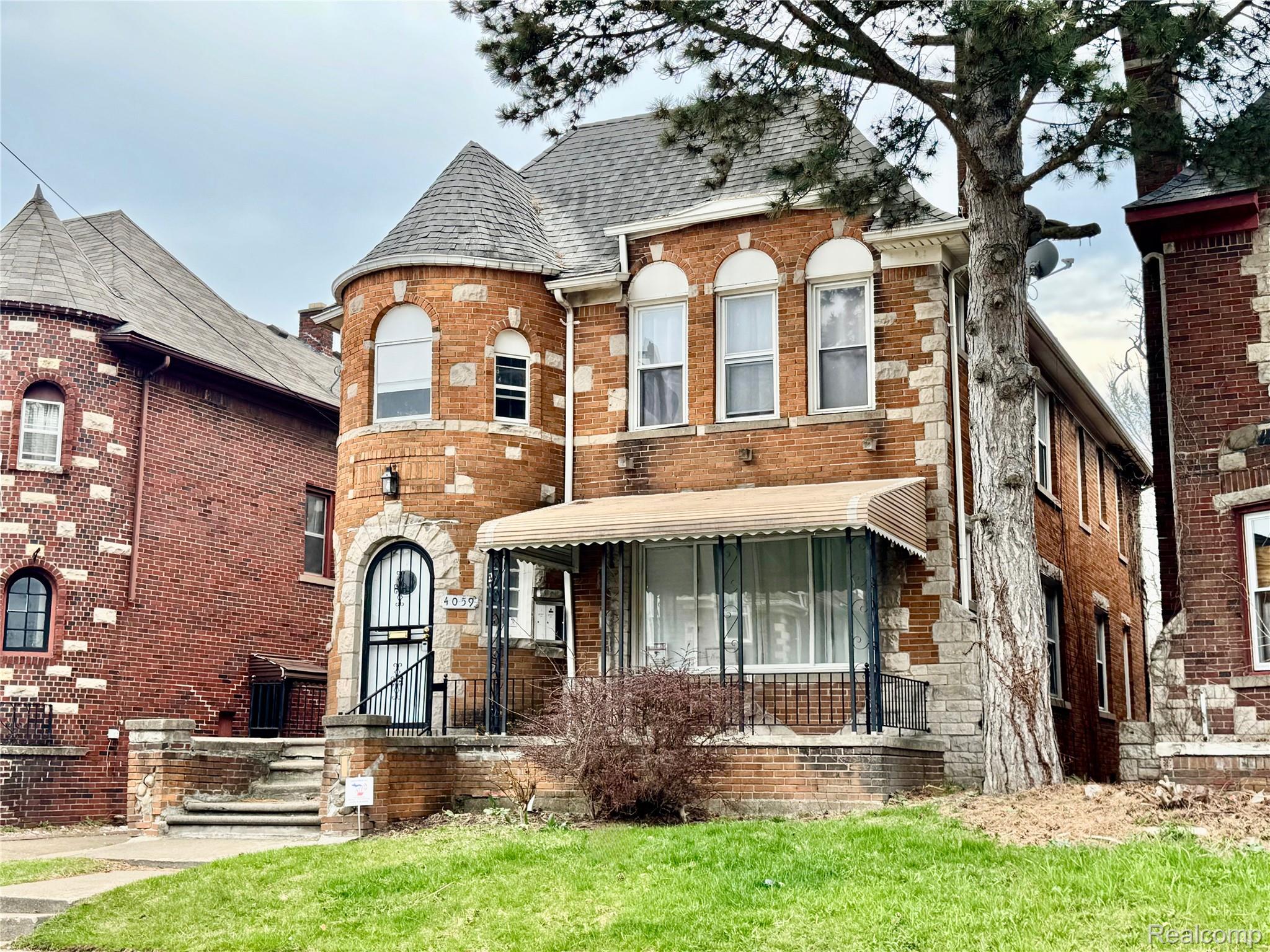 View of front of home featuring brick siding, roof with shingles, and a front yard