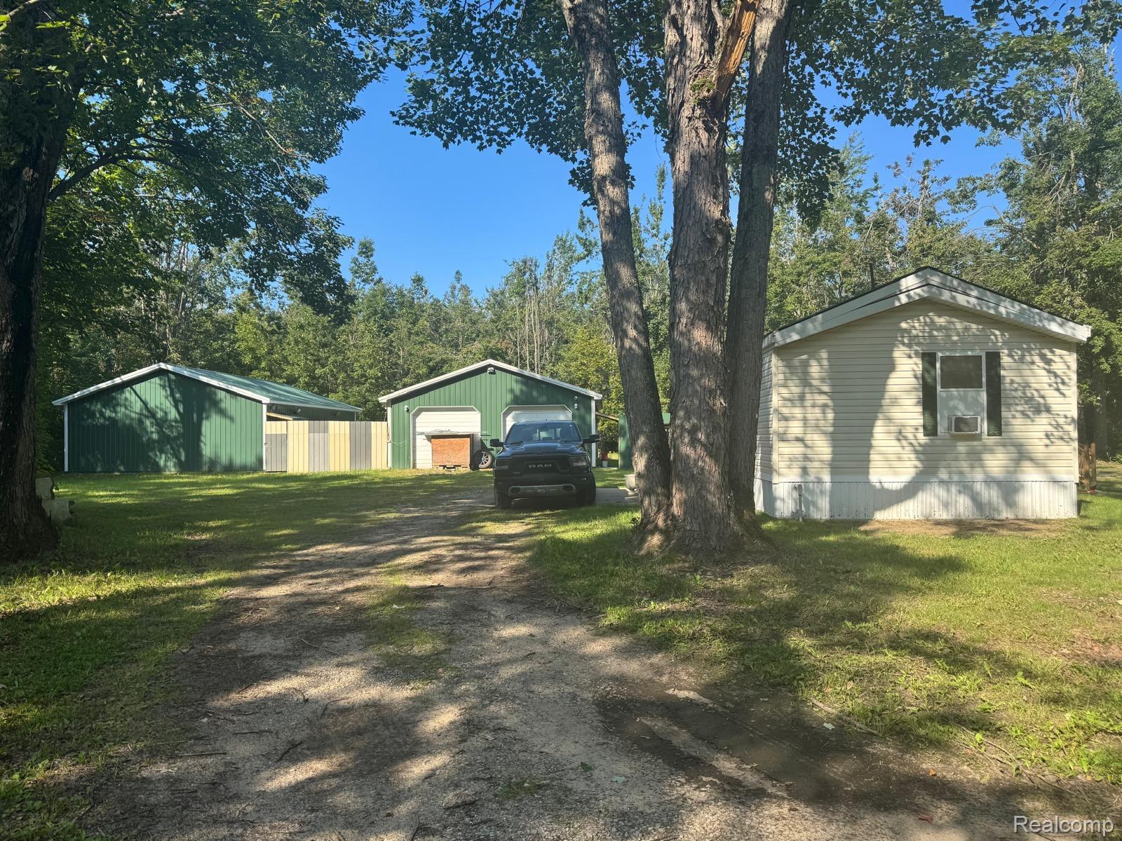 View of property exterior featuring a detached garage, an outdoor structure, a lawn, and driveway